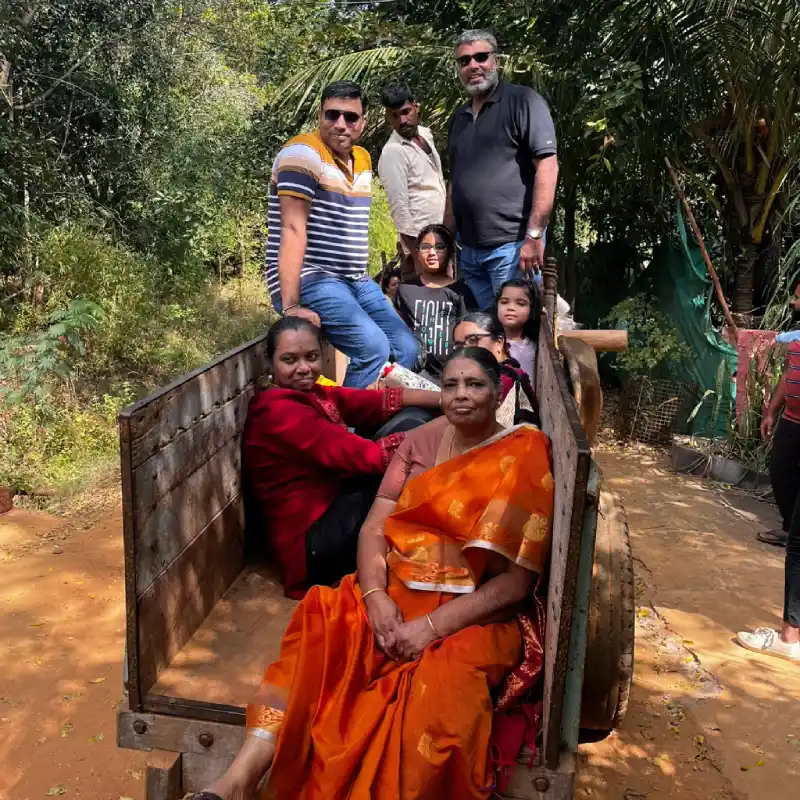 Guests riding a traditional bullock cart through farmlands at ChukkiMane