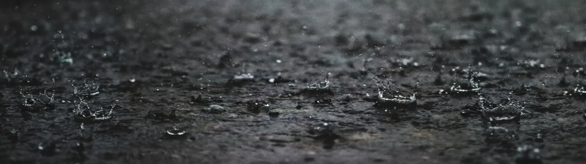 Raindrops creating ripples on rain-soaked ground Raindrops creating ripples on rain-soaked ground