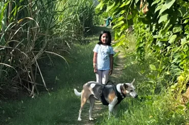 Young girl exploring a green nature trail with a friendly dog at ChukkiMane