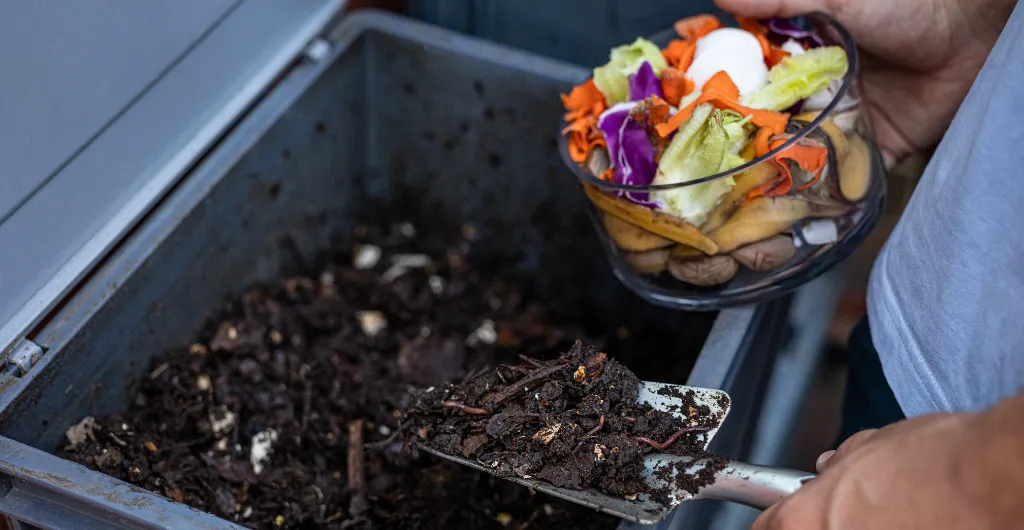 Adding vegetable scraps to a home compost bin