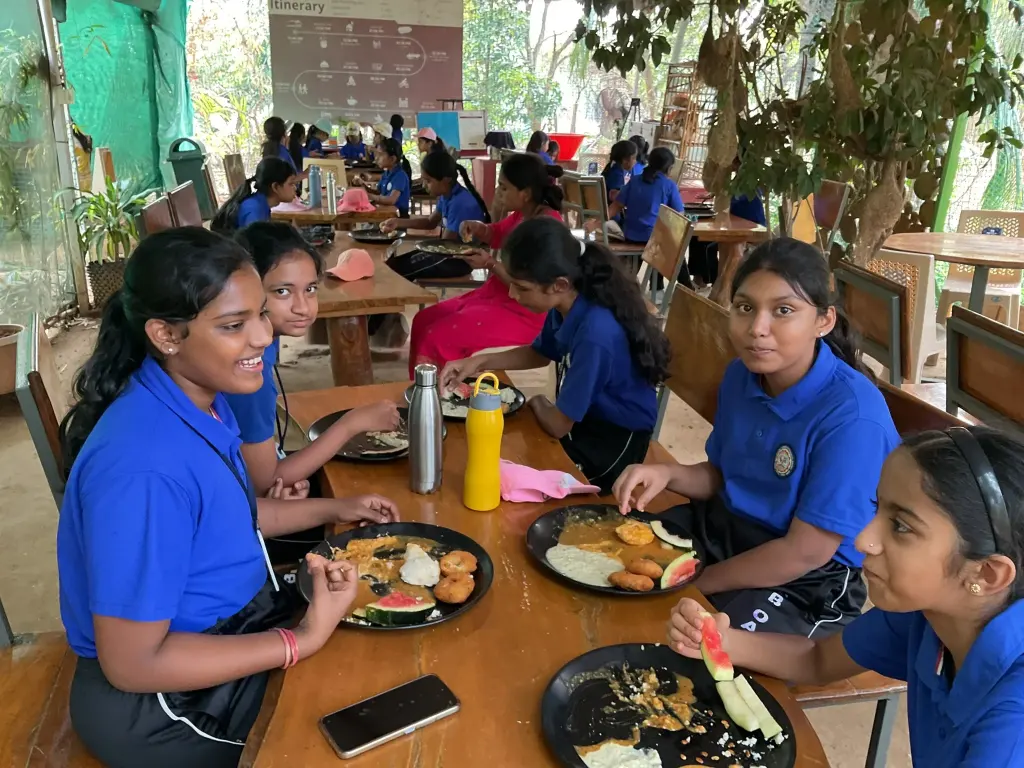 Schoolchildren sharing a traditional meal during an educational farm visit near Bangalore