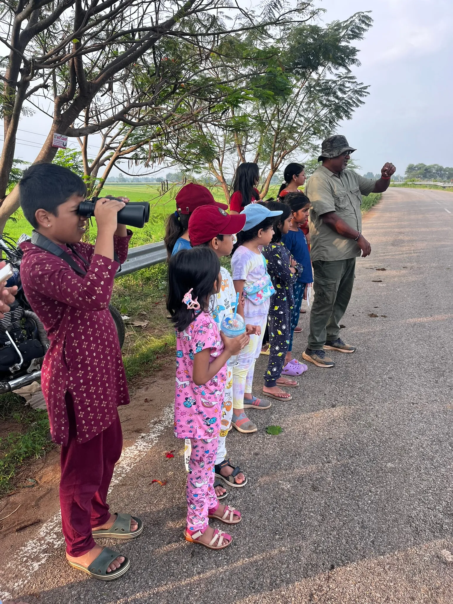 Children and adults looking for birds beside a countryside road